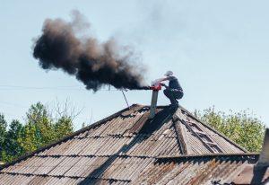 Un homme nettoie un poele à bois encrassé et trouve pourquoi, les causes et solutions